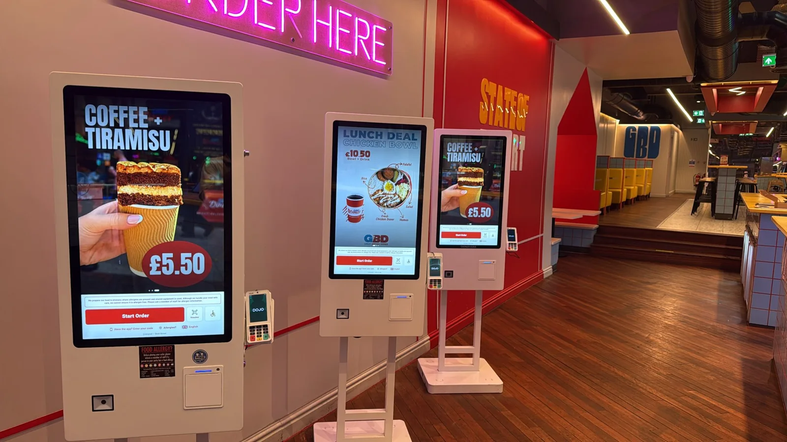 Three ZanPOS self-order kiosks at Great British Doner with card readers and 'Order here' sign