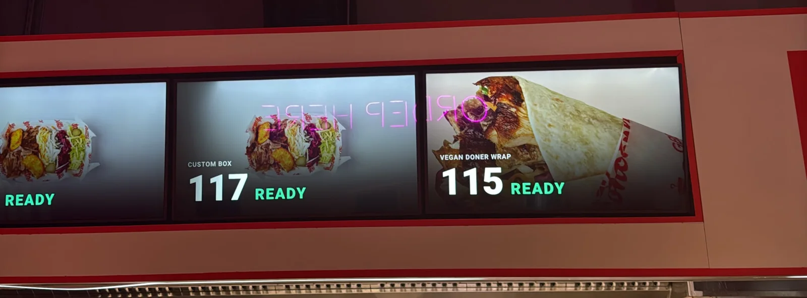Customer display screens above the Great British Doner counter showing orders 115 and 117 ready, with dish photos